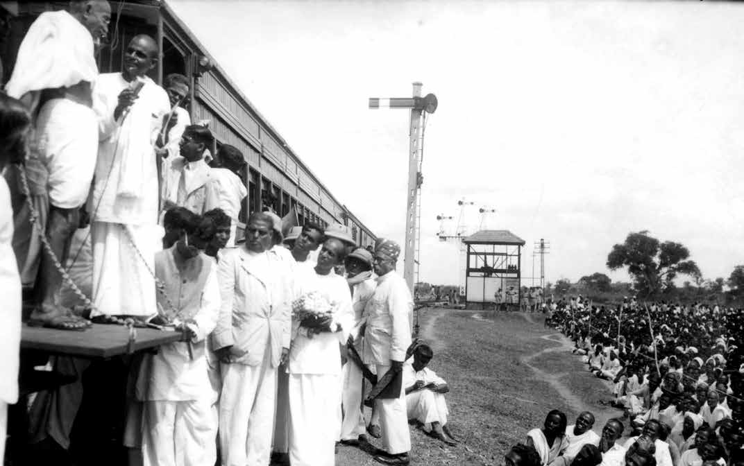 Mahatma Gandhi addressing the people from the train coach outside the station platform during his Harijan tour to South India, February 1946